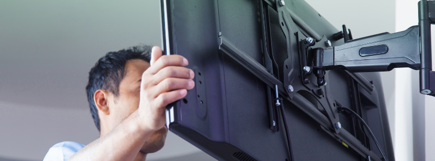 A man is installing a flat screen tv on a wall mount.