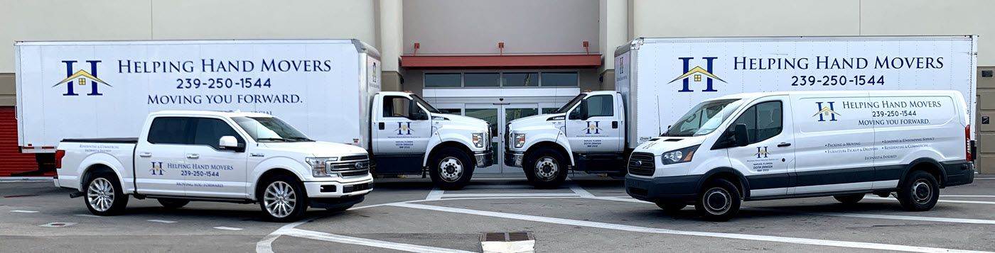 Three white trucks are parked in a parking lot in front of a building.