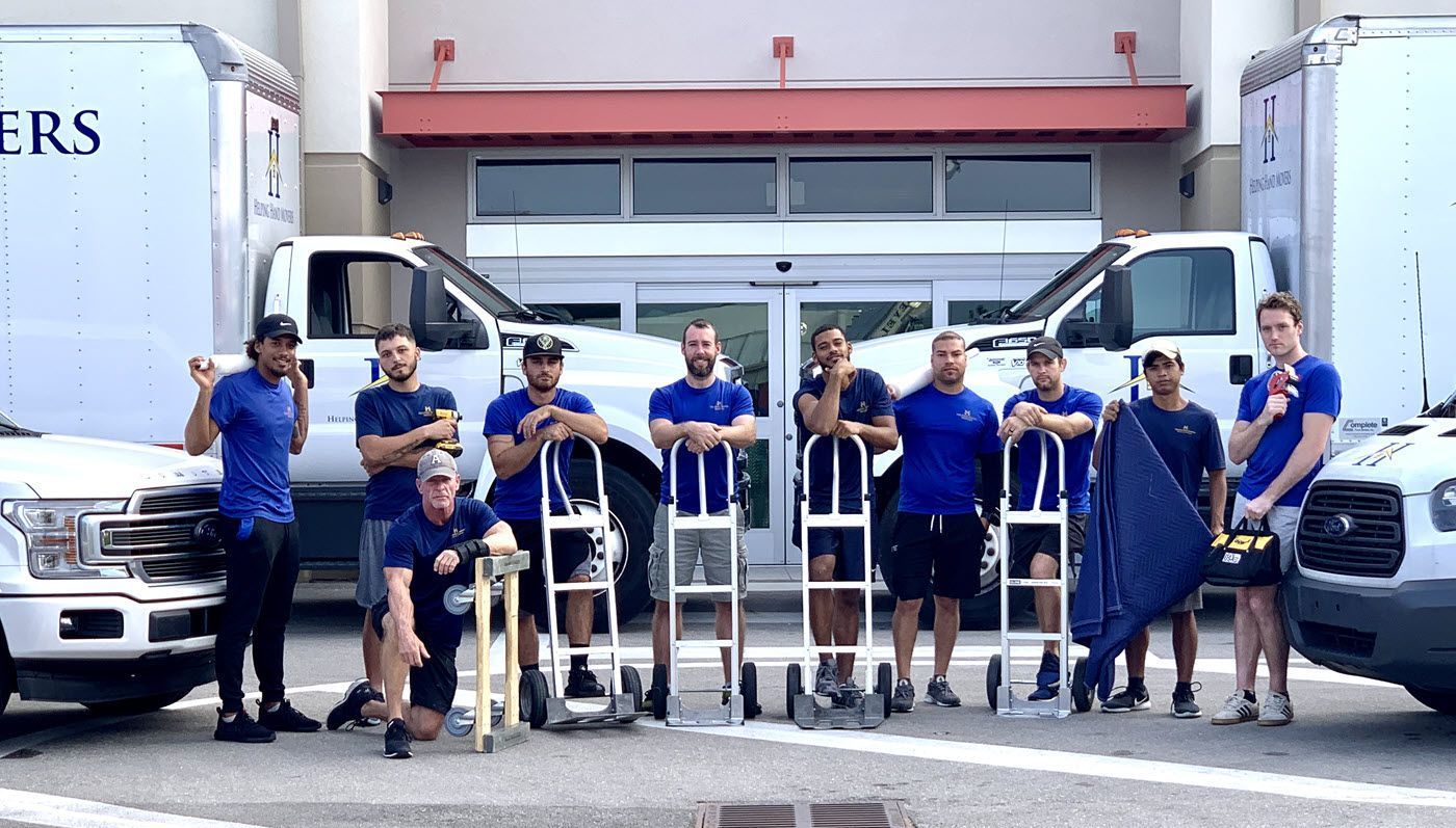 A group of men are posing for a picture in front of moving trucks.