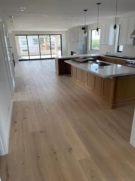 Light wood floors in a modern kitchen with a large island and sliding glass doors.