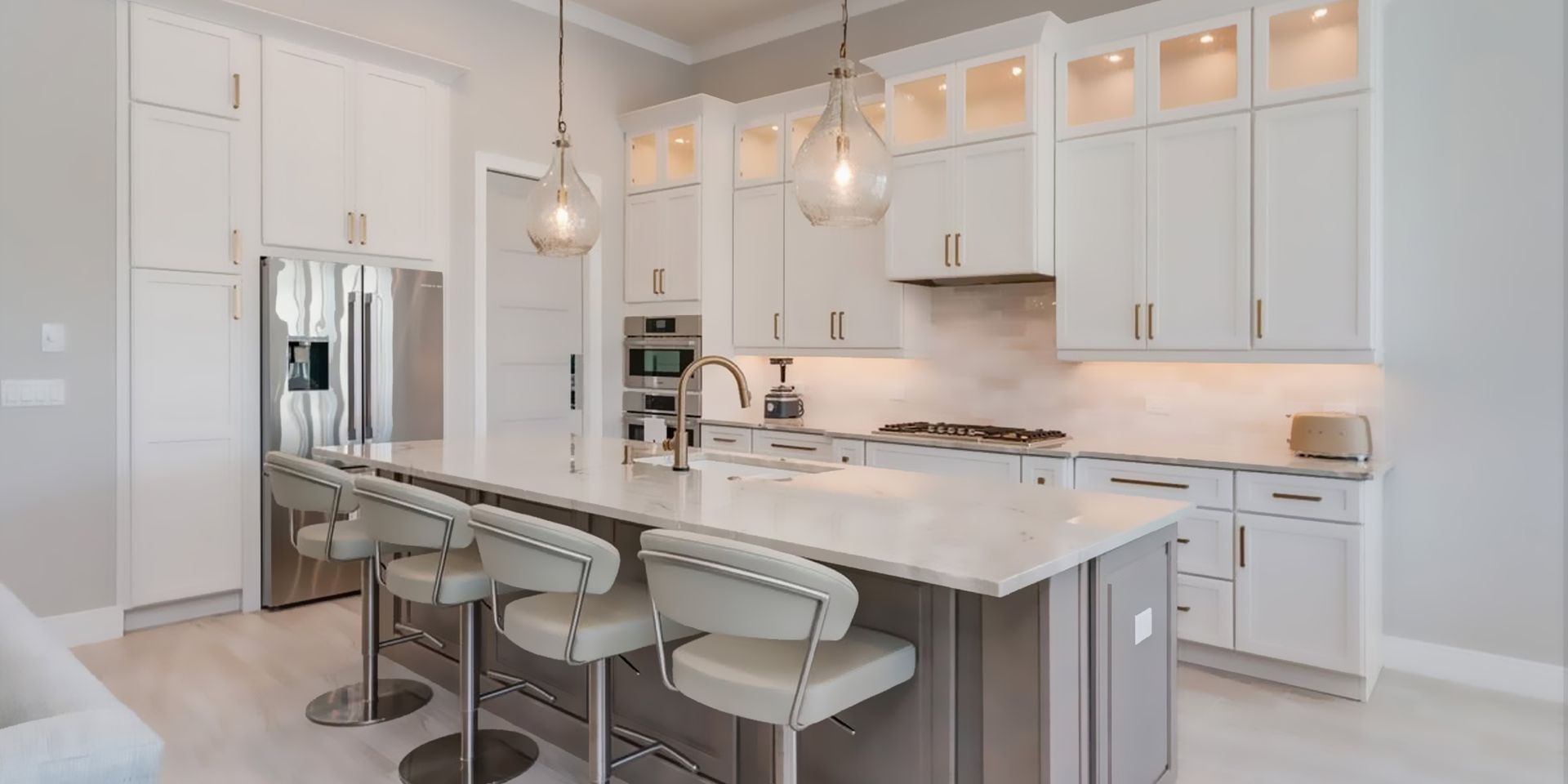 Bright modern kitchen with white cabinets, stainless appliances, island, and light wood flooring