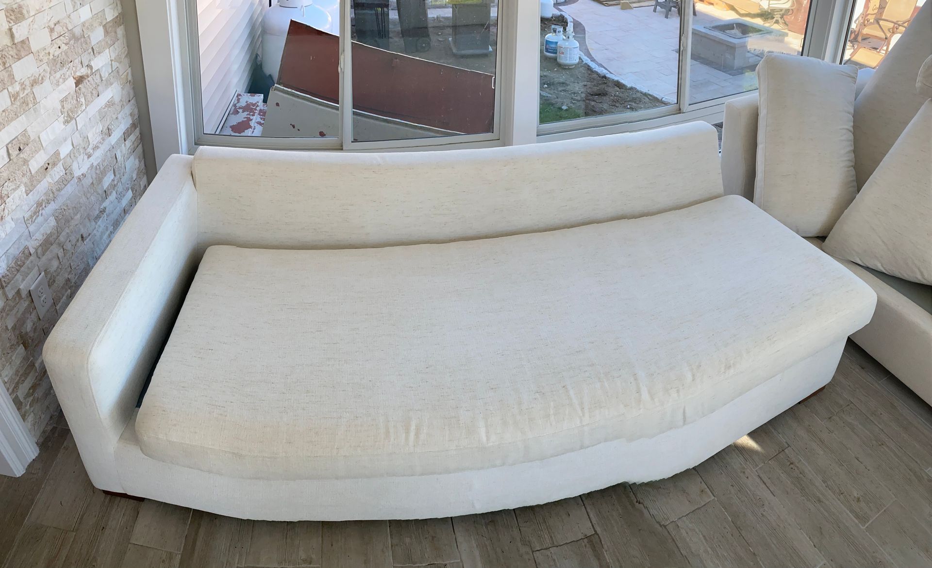 White curved sofa near a window with a light wood floor.
