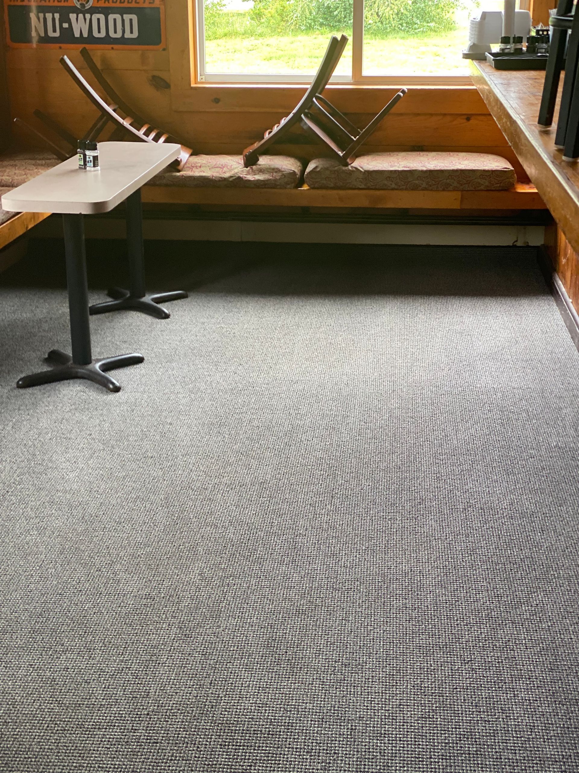 Restaurant interior with brown booths, tables, and dark carpet.