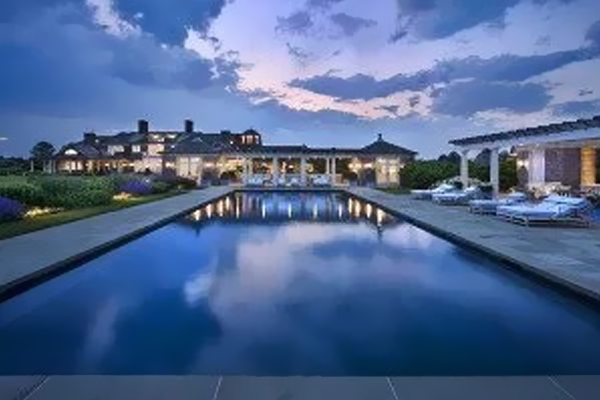A large swimming pool with a large house in the background.