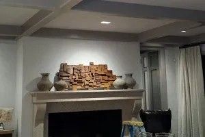 A living room with a fireplace and vases on the mantle.