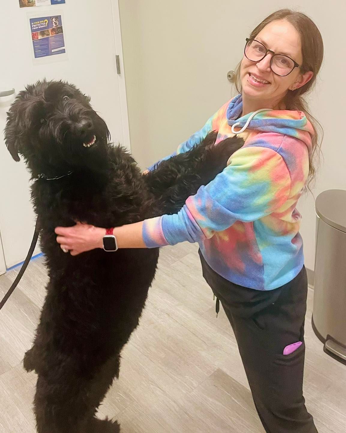 A woman is holding a black dog in her arms.