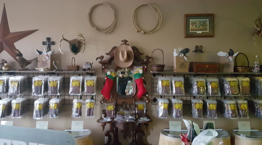 A store display with shelves of packaged items, ropes, a star, and a cowboy hat hanging on a clock.