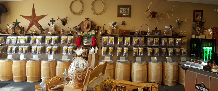 Western-themed store interior with shelves of products over wooden barrels. Decorations include a star, ropes, and antlers.