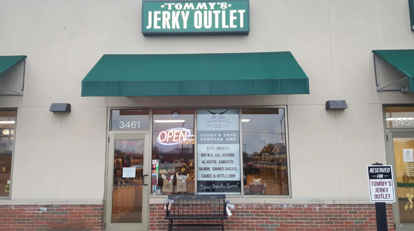 Tommy's Jerky Outlet store front with green awning and open sign.