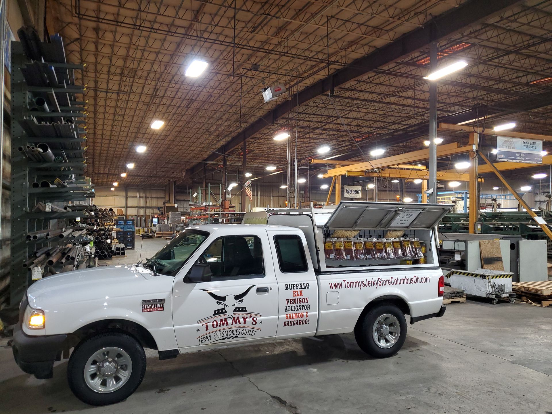 White Ford Ranger truck in a warehouse, with logo and equipment in the bed.
