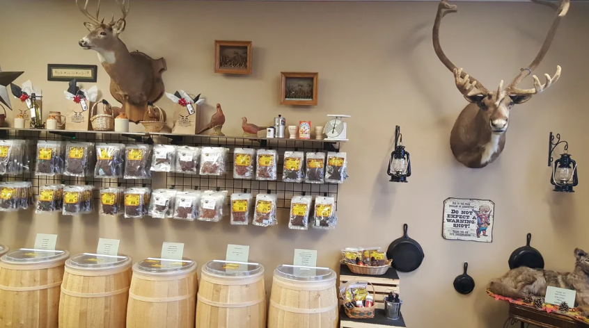 A store display with mounted deer heads, barrels, and packaged jerky.