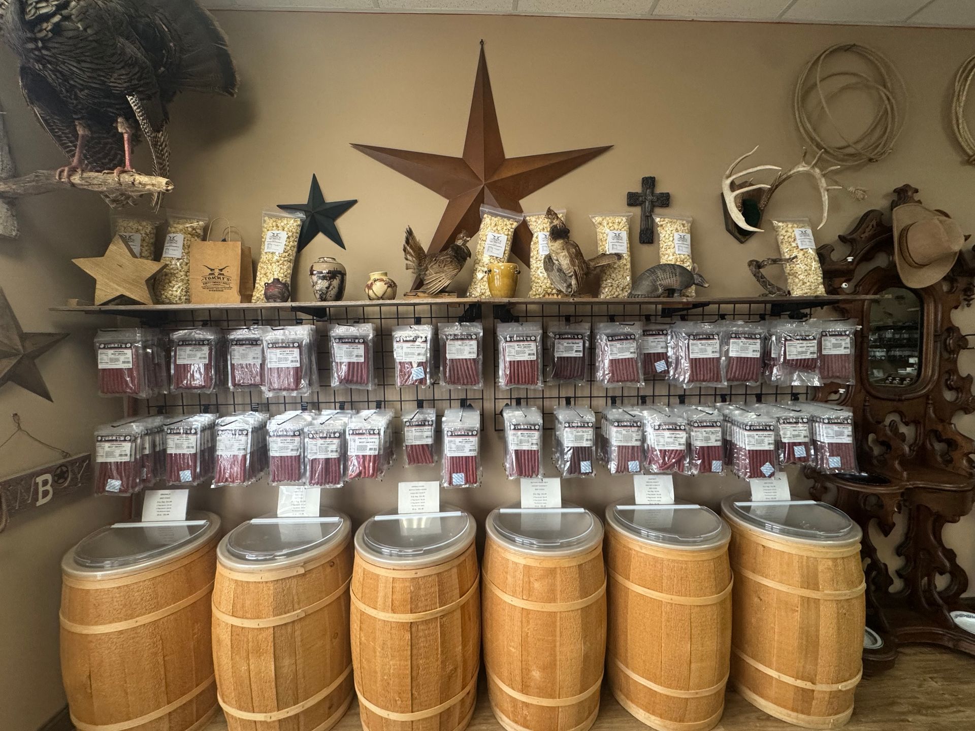 Trays of various nuts for sale, including peanuts, walnuts, and almonds, with small paper bags.