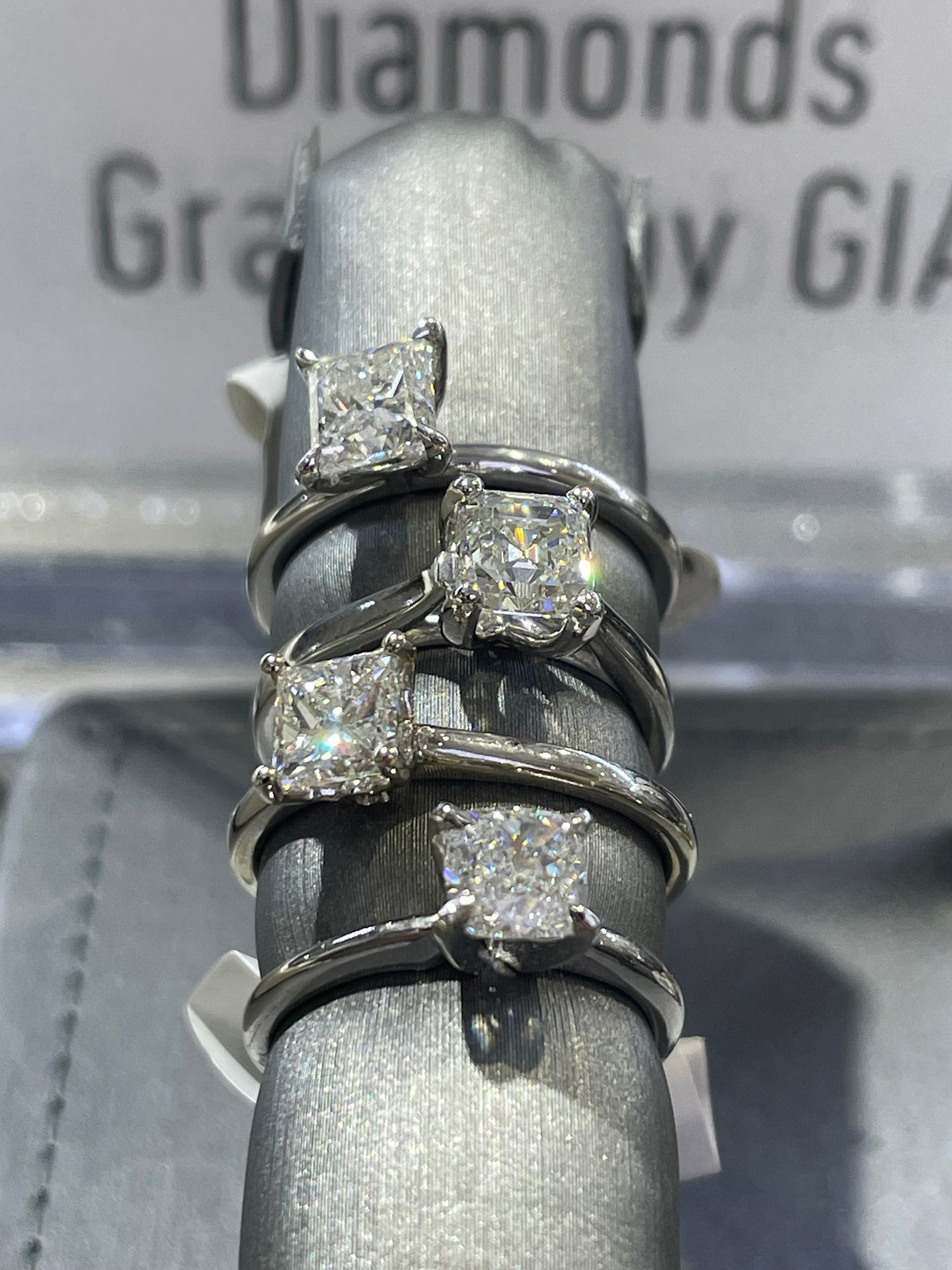 Four diamond rings on a gray display stand