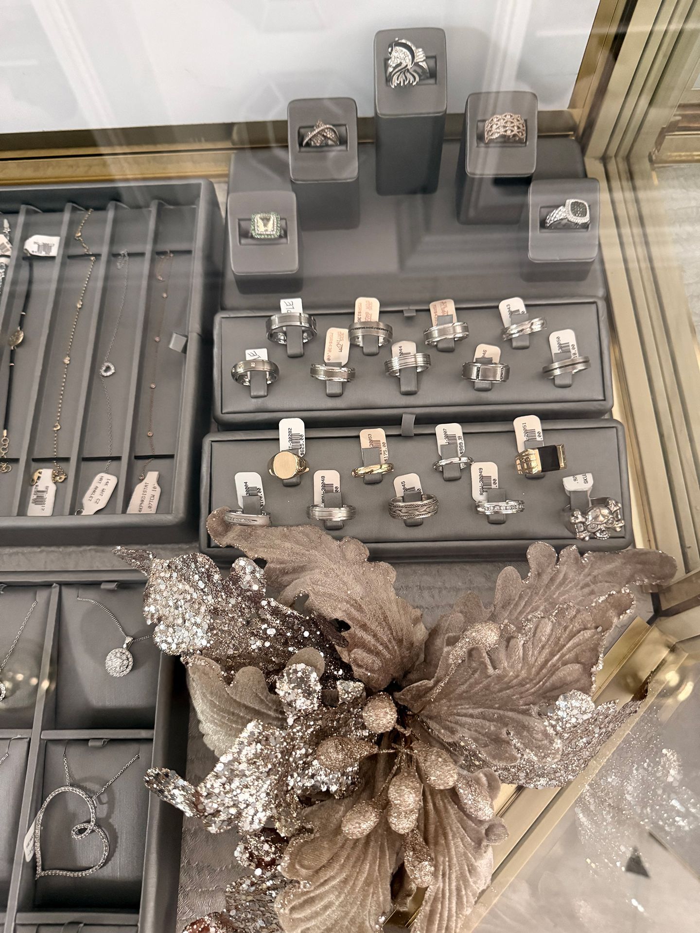 Jewelry display case with rings and necklaces on gray velvet trays