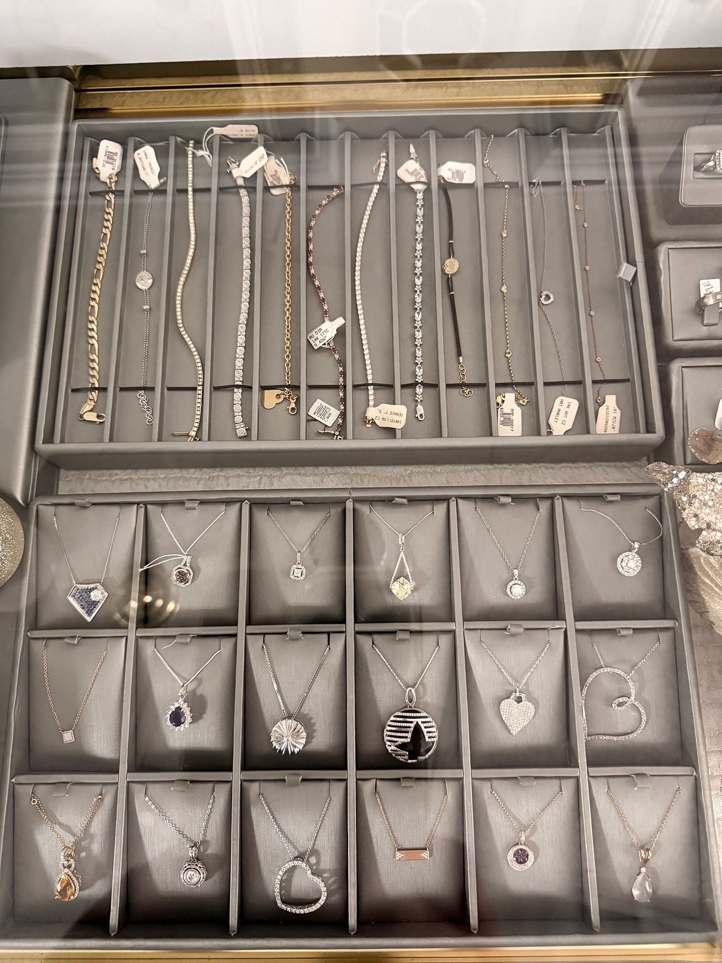 Jewelry display case with necklaces and bracelets arranged on gray fabric