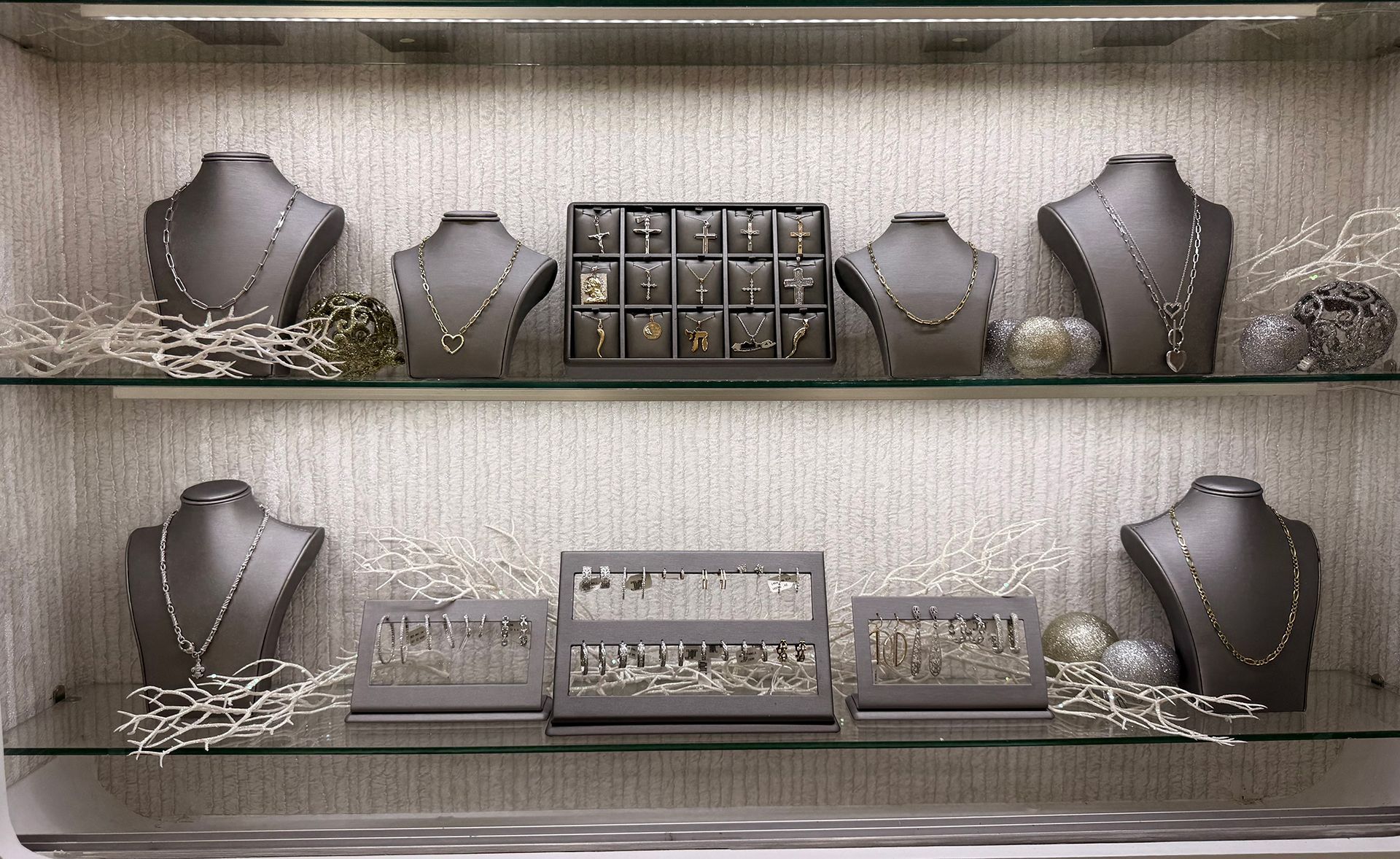 Jewelry display case with necklaces and earrings on gray busts and stands