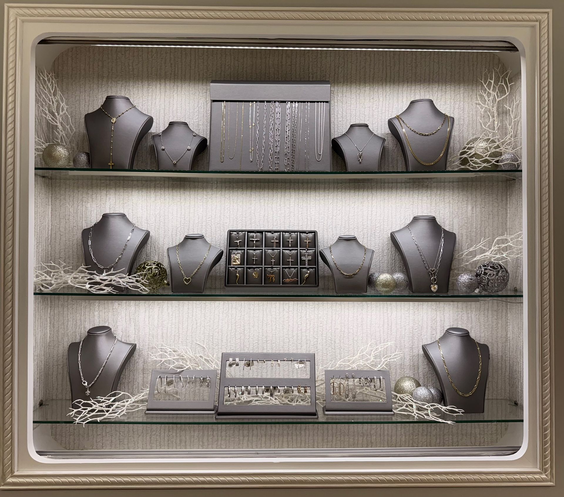 Jewelry display case with necklaces on mannequins, jewelry boxes, and decorative twigs