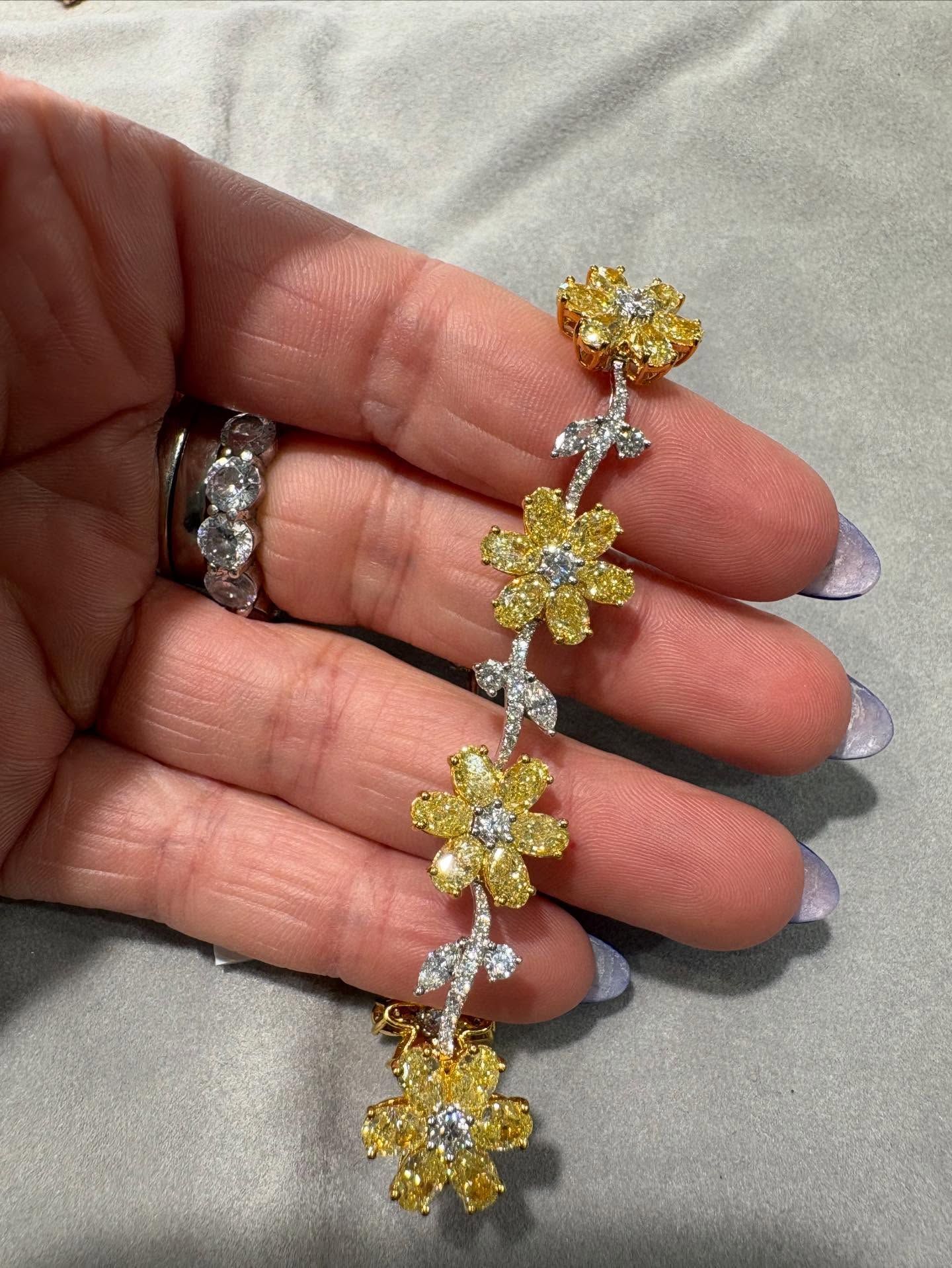 Hand holding a diamond and yellow gemstone flower bracelet.