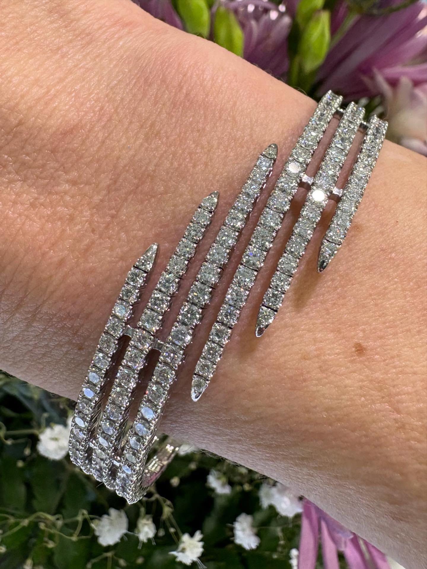 Diamond bracelet on a wrist, with a floral background.