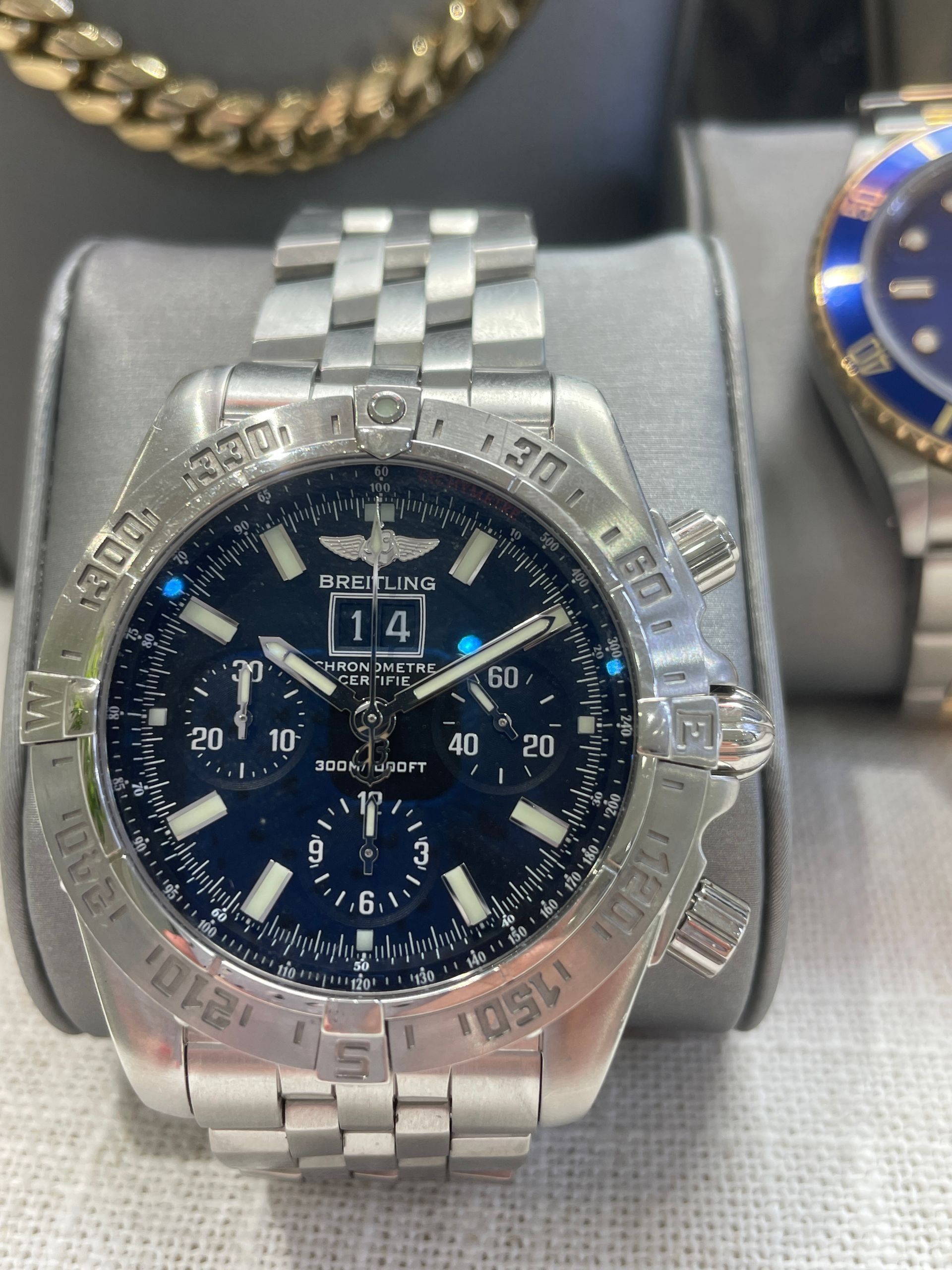 Wristwatch with dark blue dial and metal link bracelet on a display stand