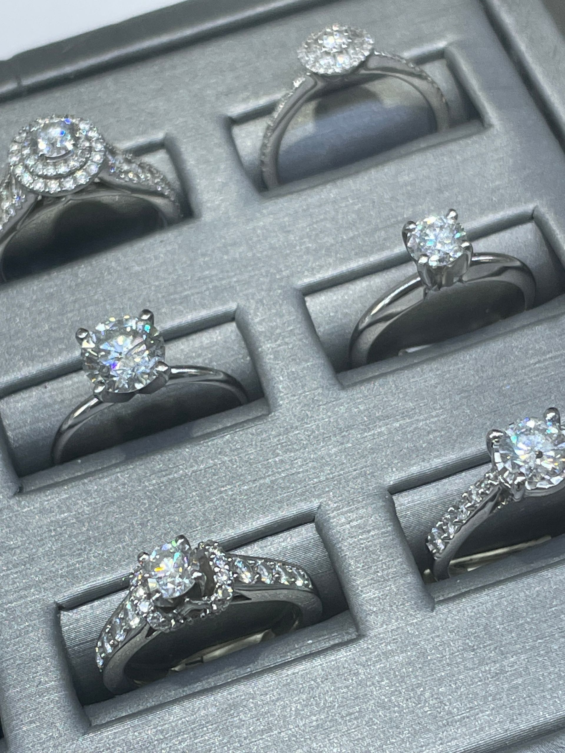 Assorted diamond rings displayed in a gray jewelry tray