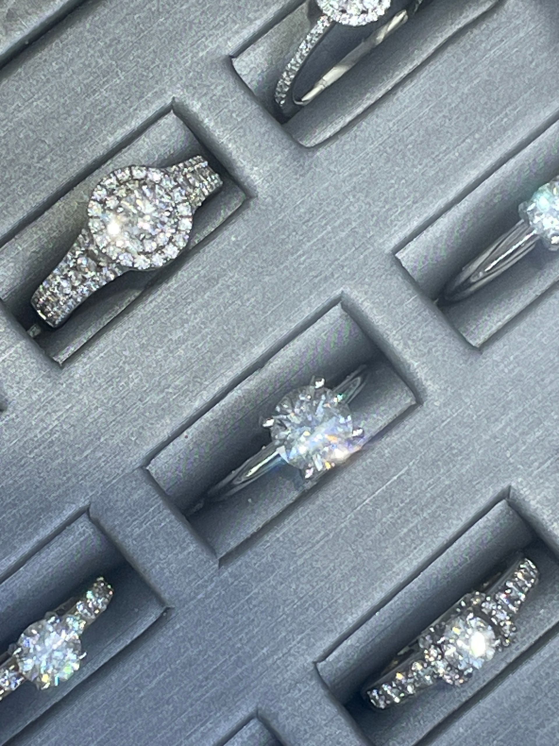 Assorted diamond rings displayed in a gray jewelry tray