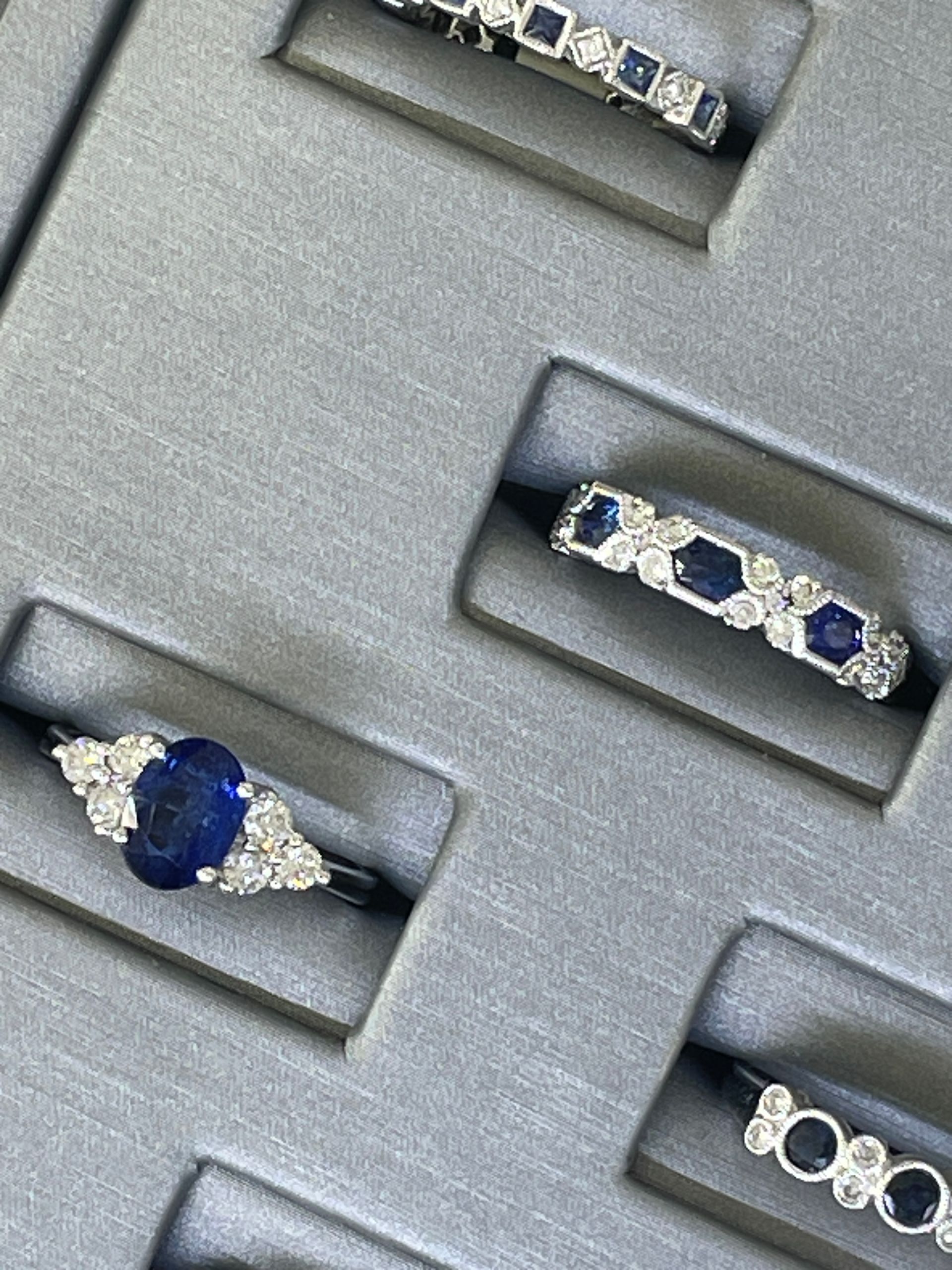 Jewelry display with silver rings set with blue and clear gemstones in gray slots
