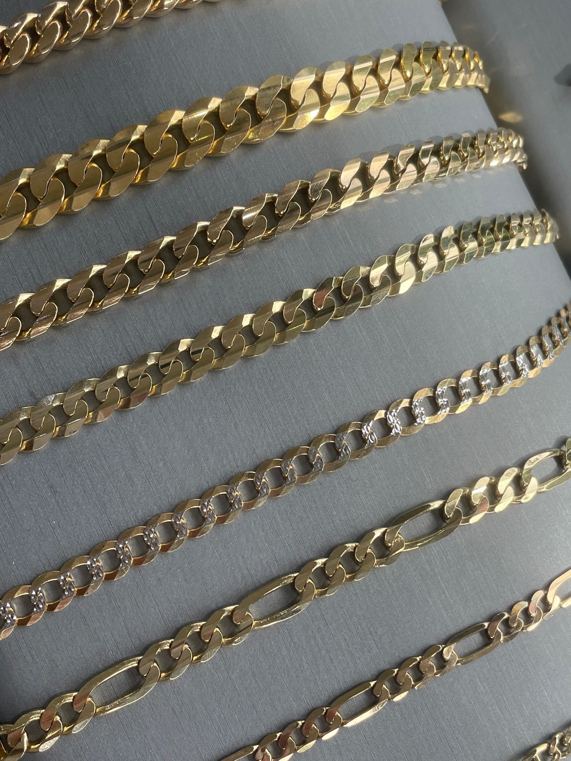Rows of gold chain necklaces on a light gray display background