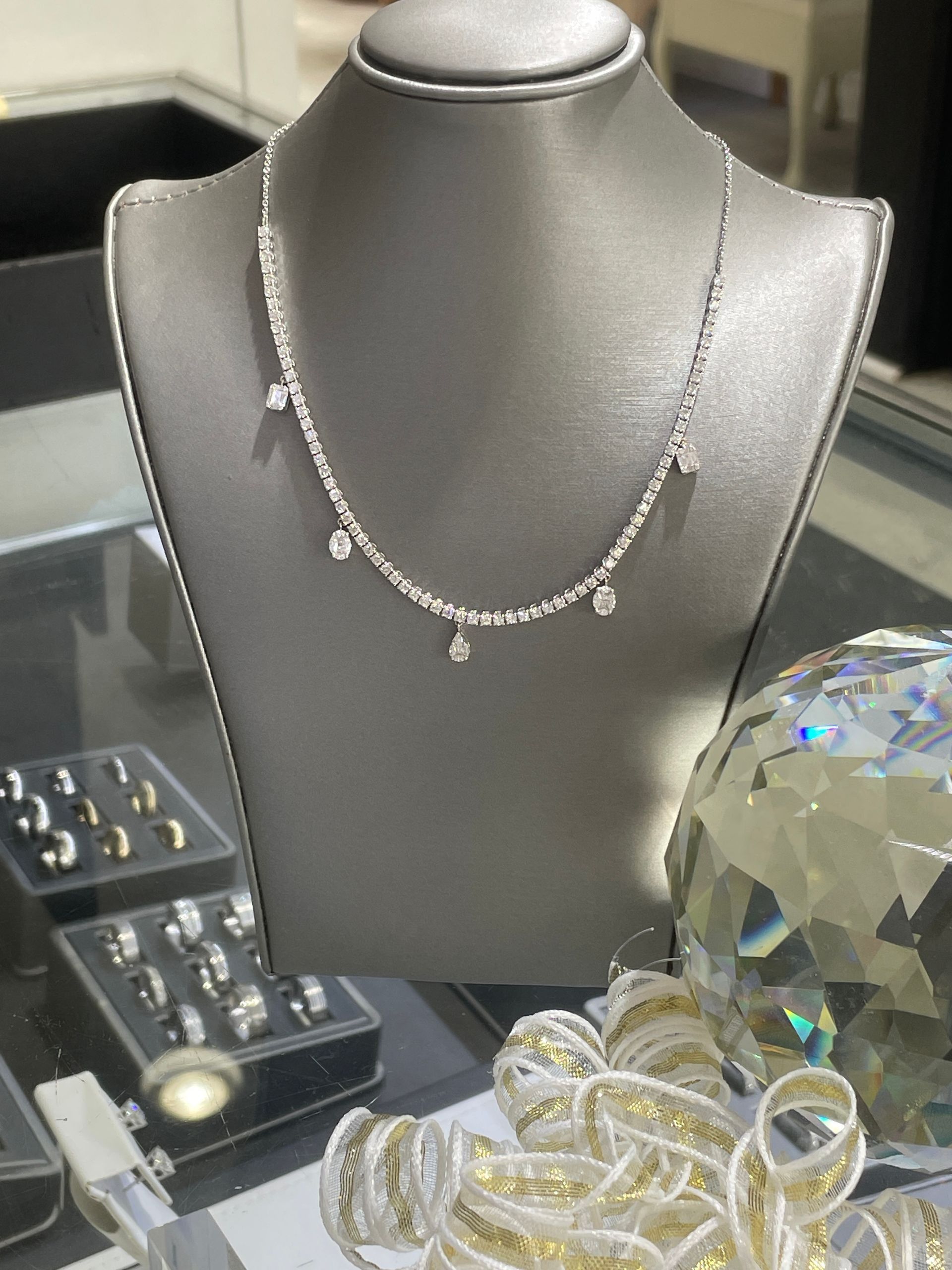 Silver necklace display beside rings and a crystal ornament.
