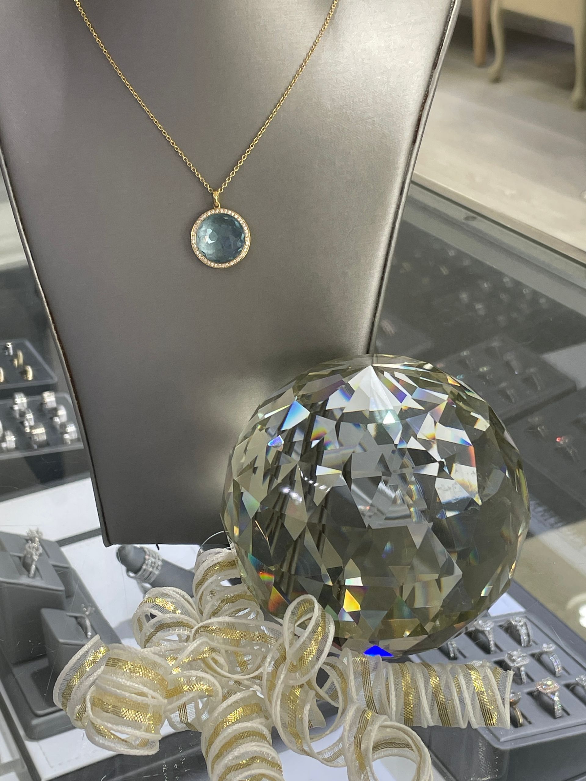 Jewelry display with a blue pendant necklace and large faceted crystal orb on a tray