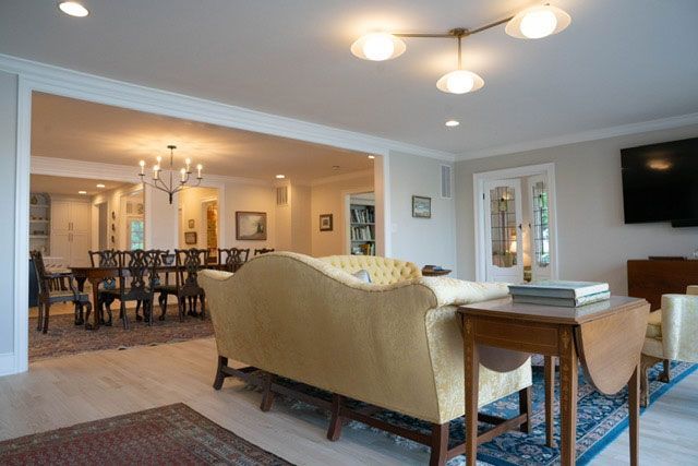 Spacious living room with beige sofa, blue rug, dining area, and wall-mounted TV