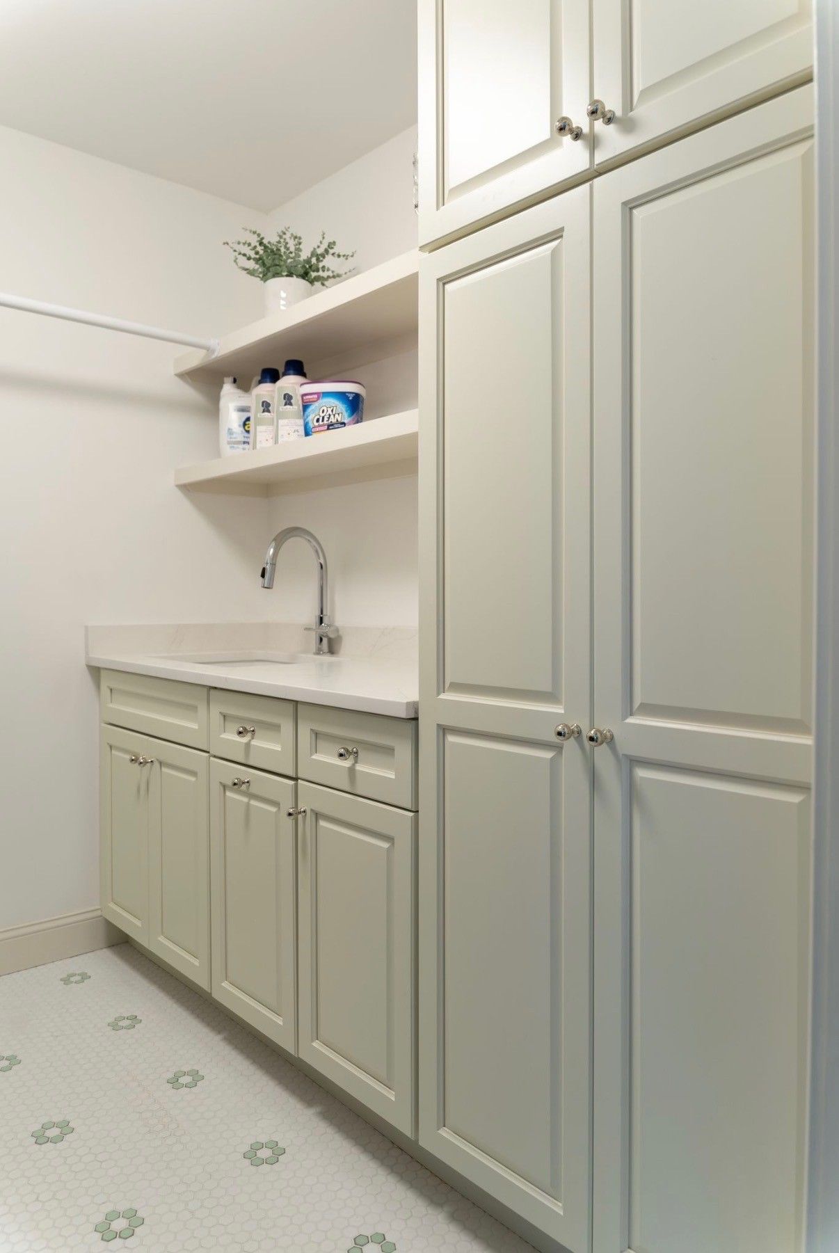 Beige laundry room with built-in cabinets, open shelves, sink, and washer-dryer hookups