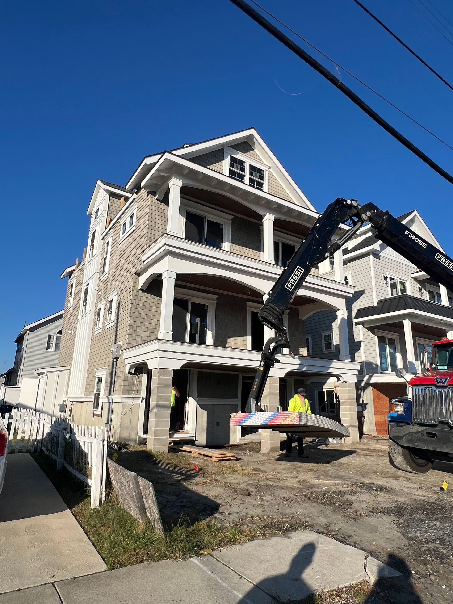Victorian house under renovation with excavator lifting debris beside the front porch