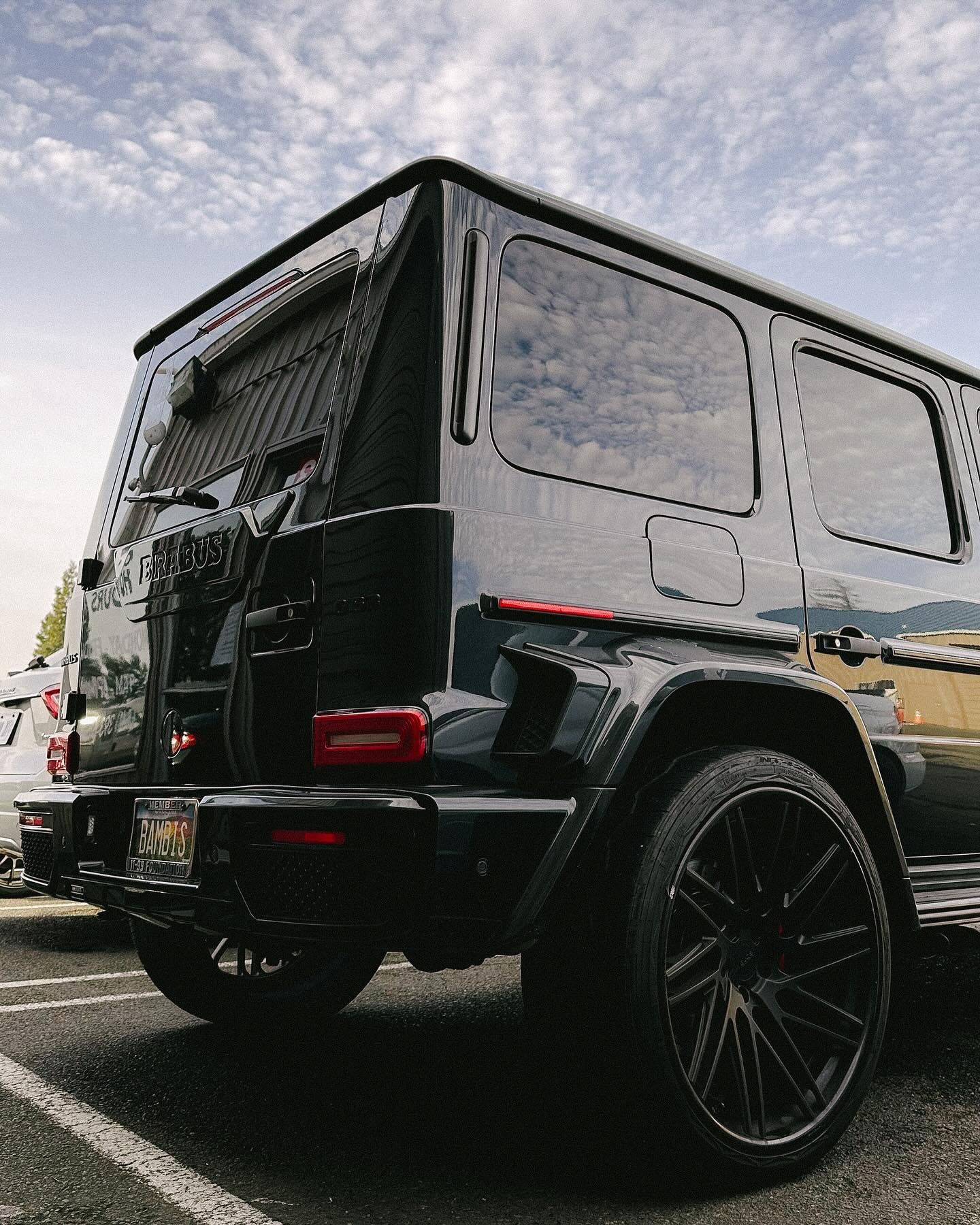 Black Mercedes-Benz G-Wagon SUV with black rims parked in a parking lot on a cloudy day.