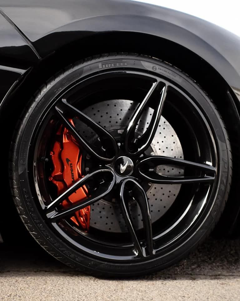 Black car wheel with glossy black rim and orange brake caliper.