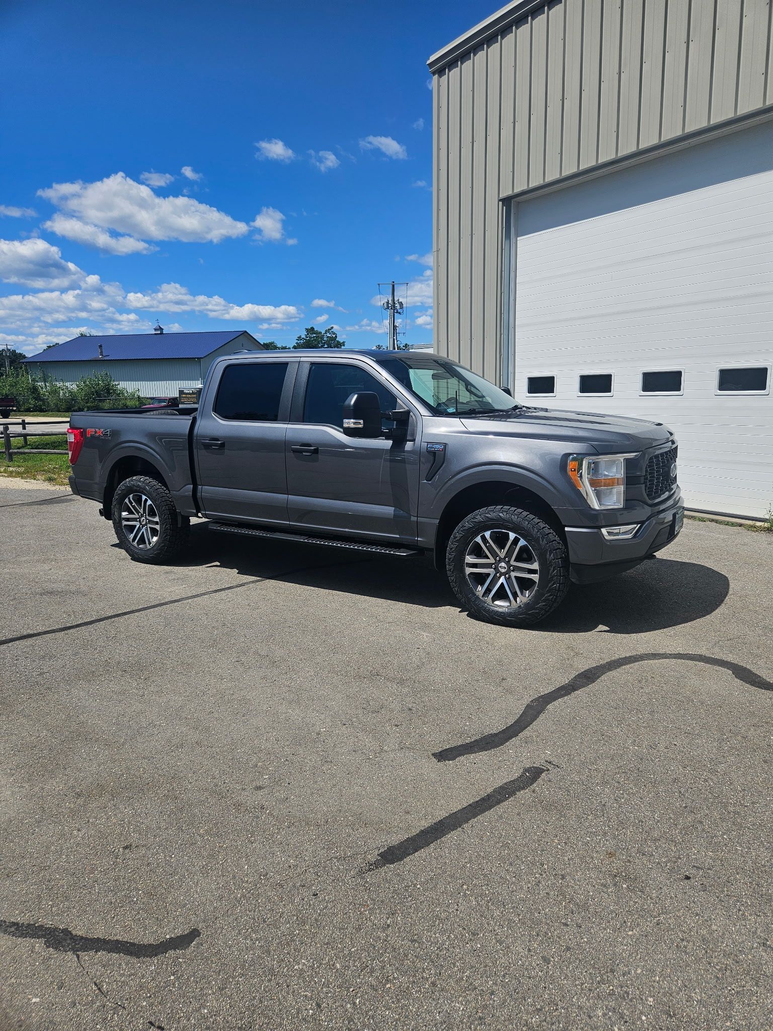 A gray ford f150 truck is parked in front of a white garage door.