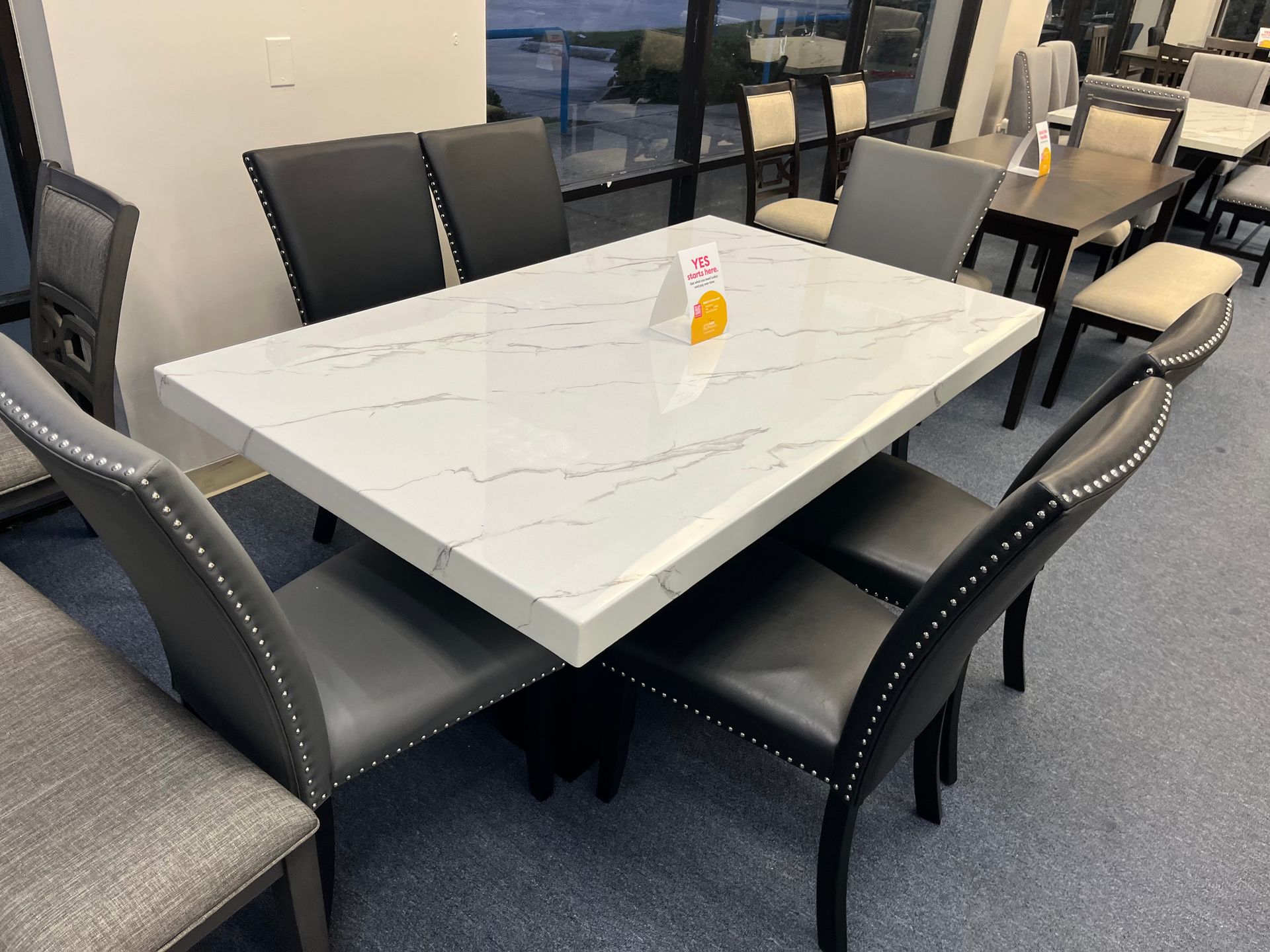 Modern dining table with black chairs in a showroom, with a small centerpiece on top