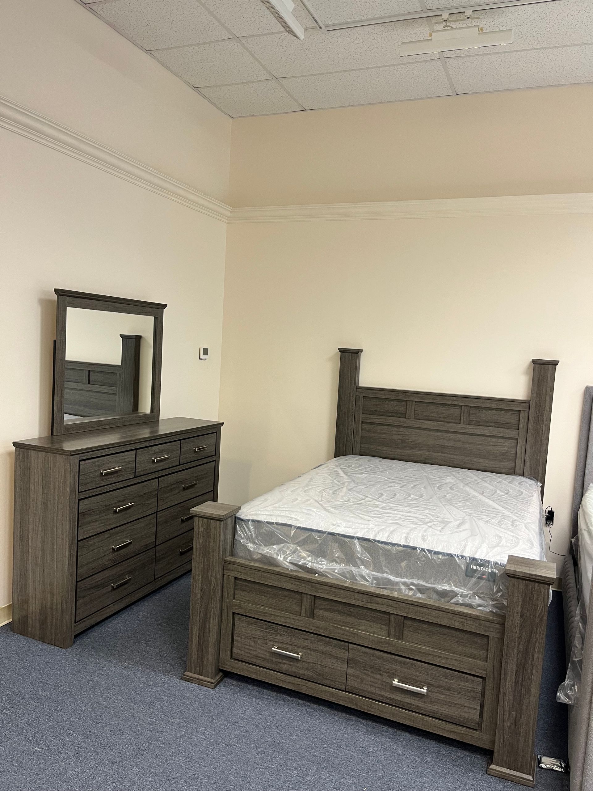 Bedroom with dark wood bed, dresser, and mirror in a plain beige room
