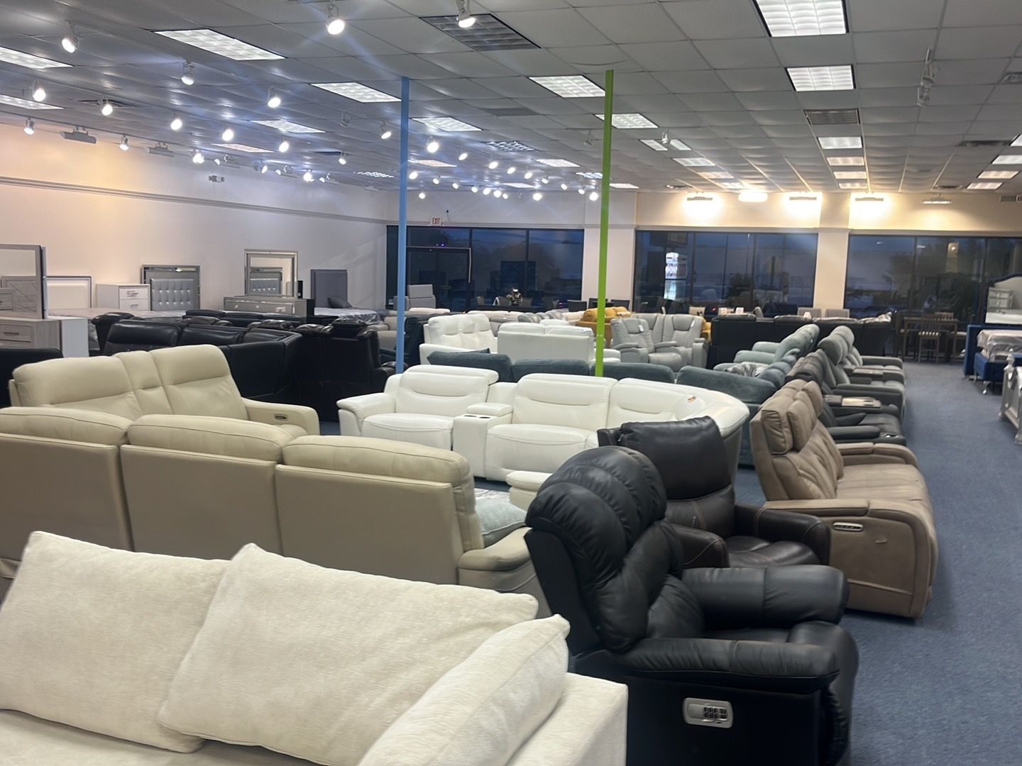 Furniture showroom with rows of beige and black sofas under bright ceiling lights