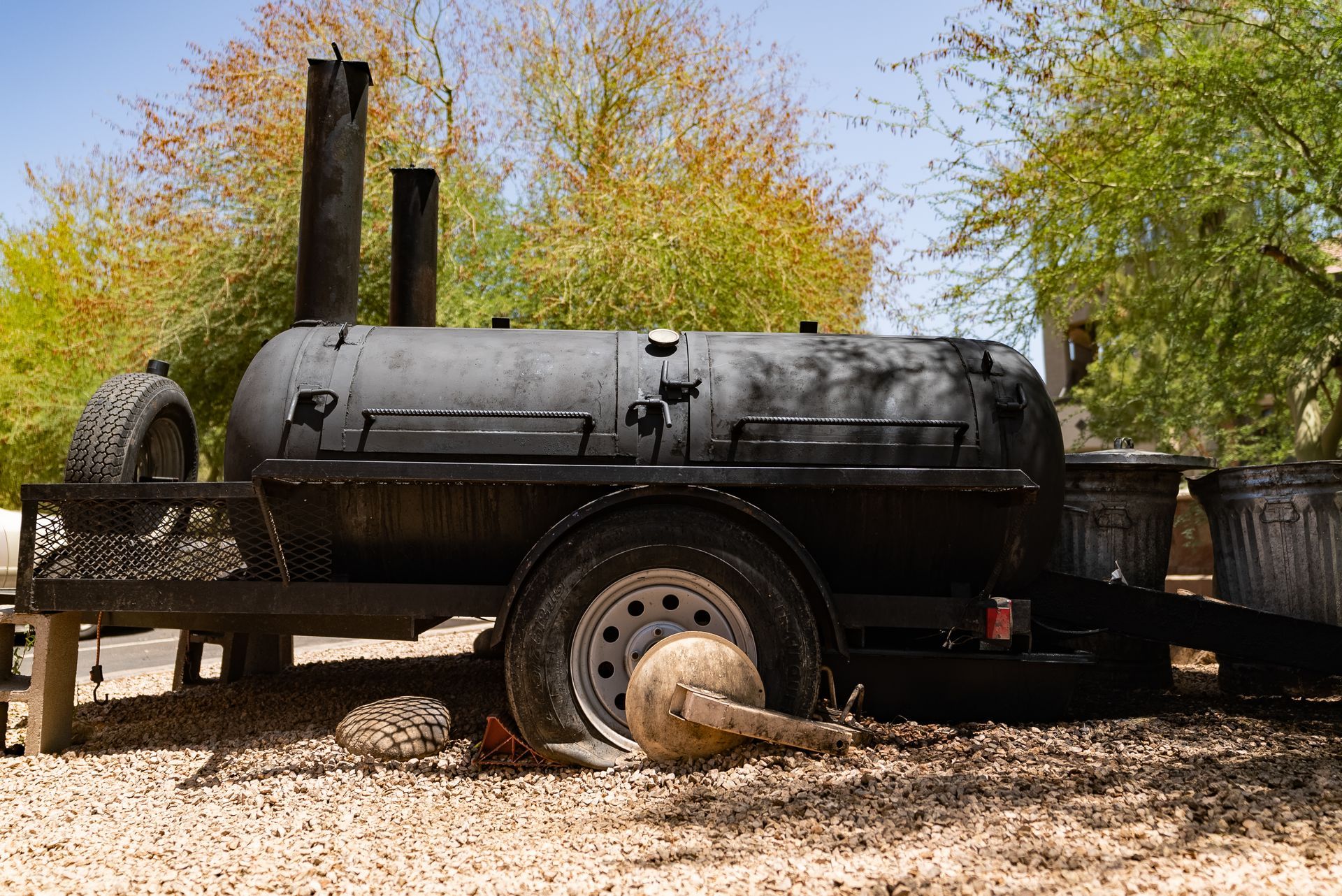 Large black smoker on trailer, outdoors.