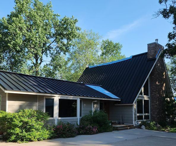 A house with a black roof and a blue sky in the background