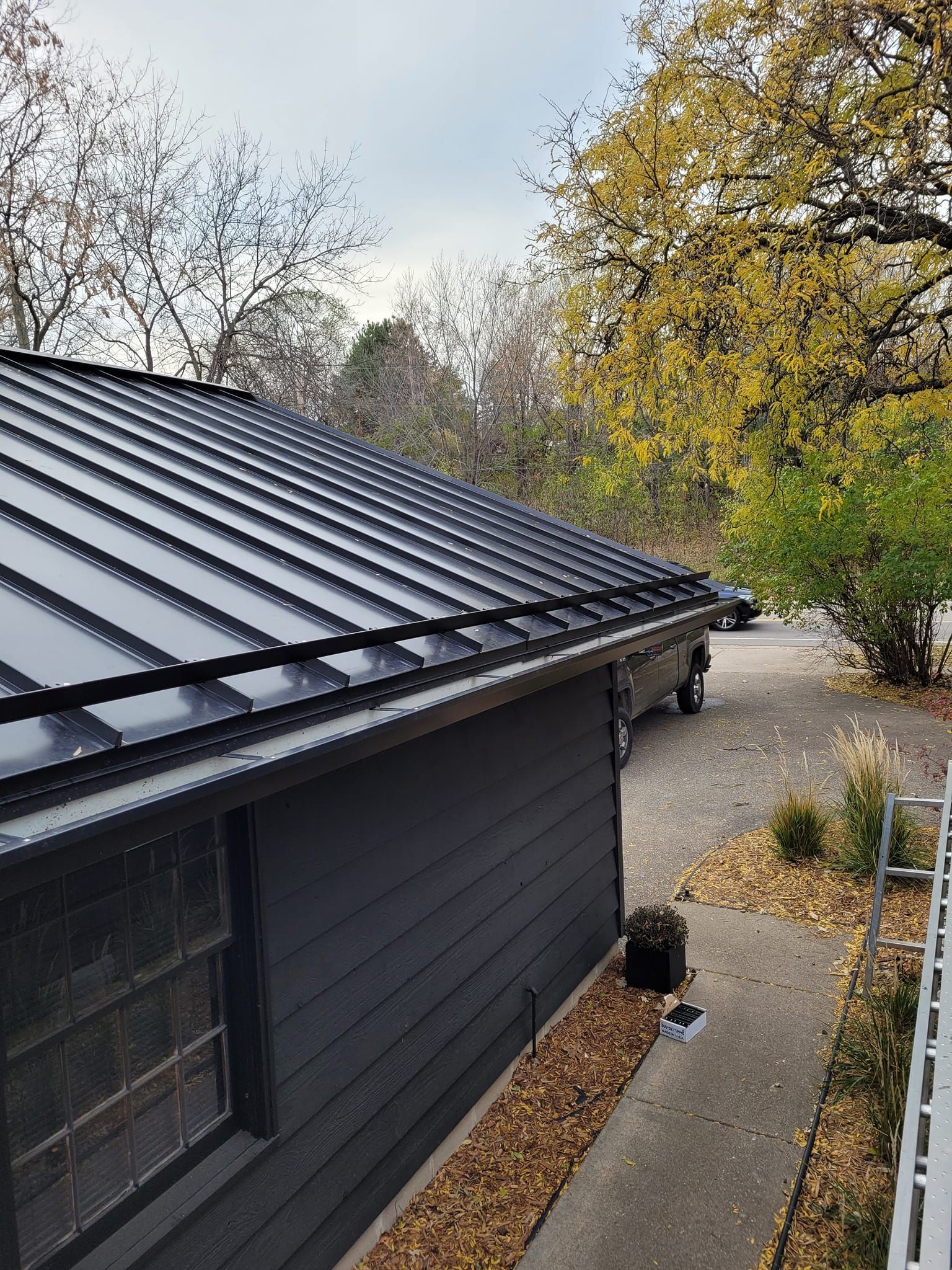 A black house with a black roof and a car parked in front of it.