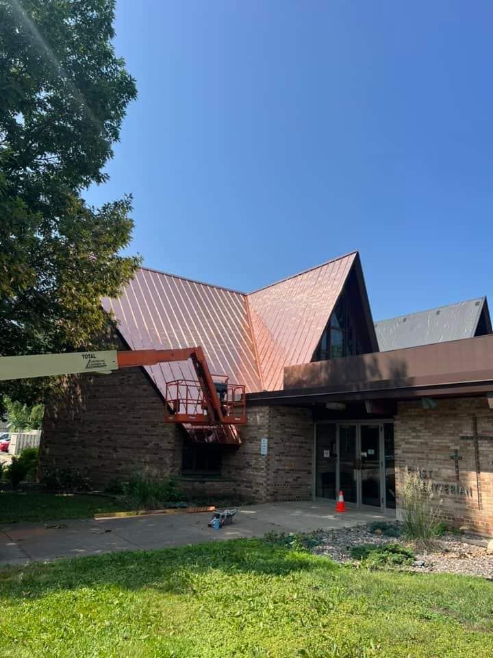 A large brick building with a copper roof is being painted.