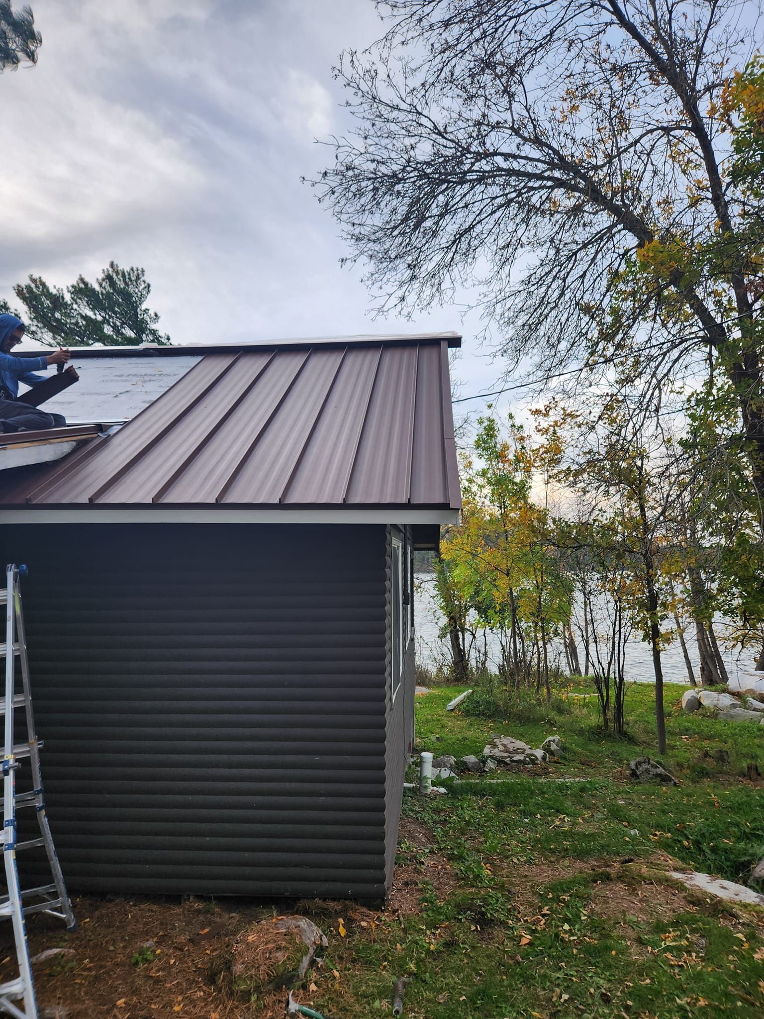 A man is working on the roof of a shed.