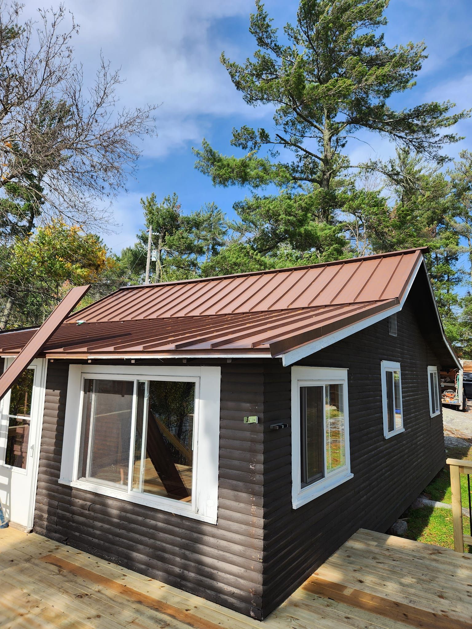 A small brown house with a red roof is surrounded by trees.