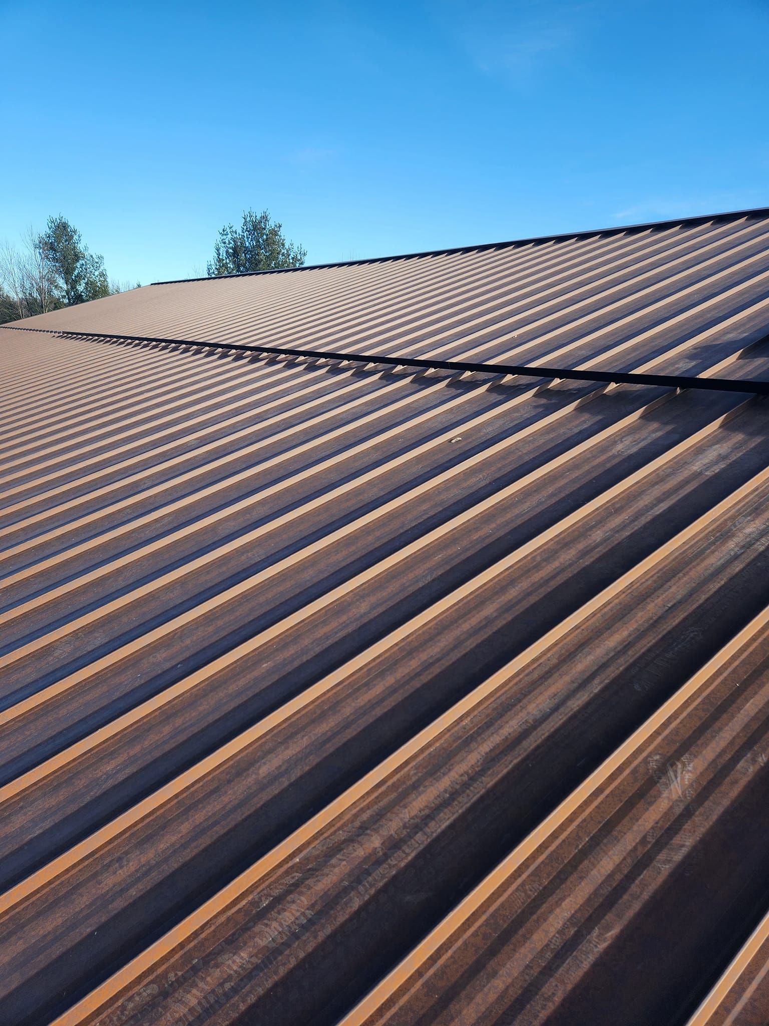A close up of a metal roof with a blue sky in the background