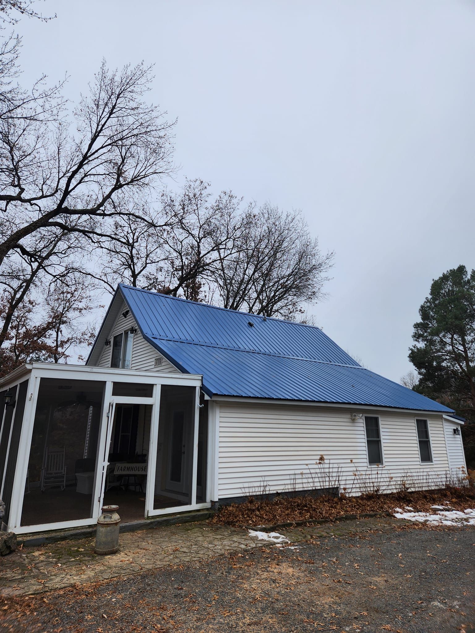 A white house with a blue roof and a screened in porch.