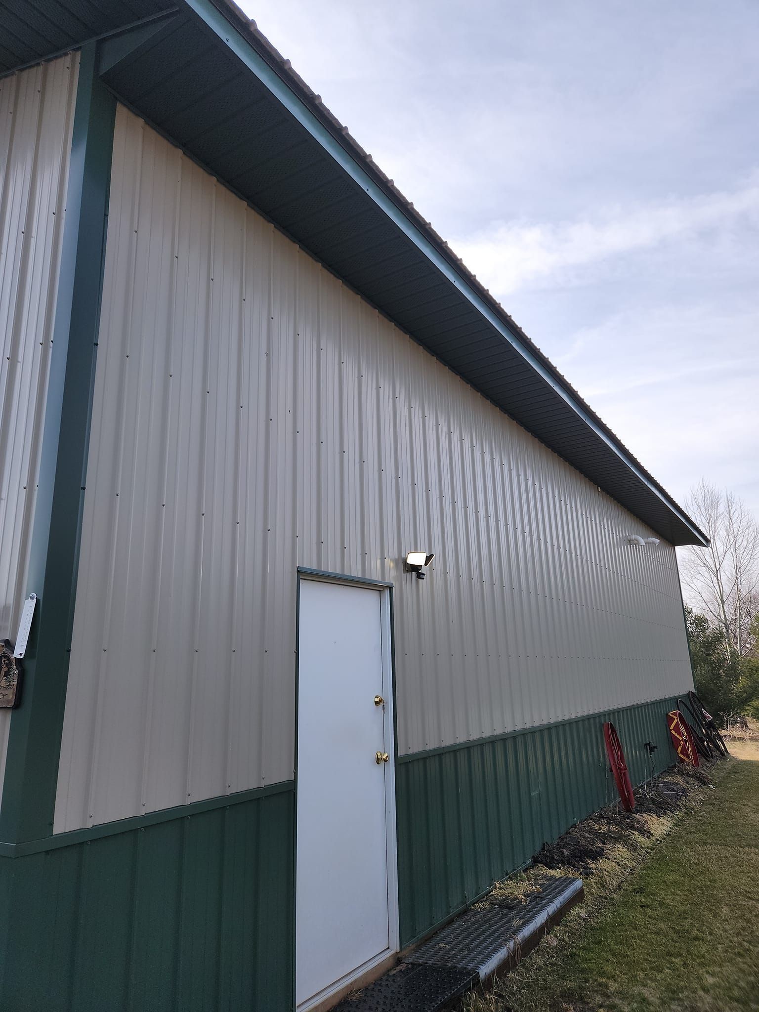 A large metal building with a white door and green trim.