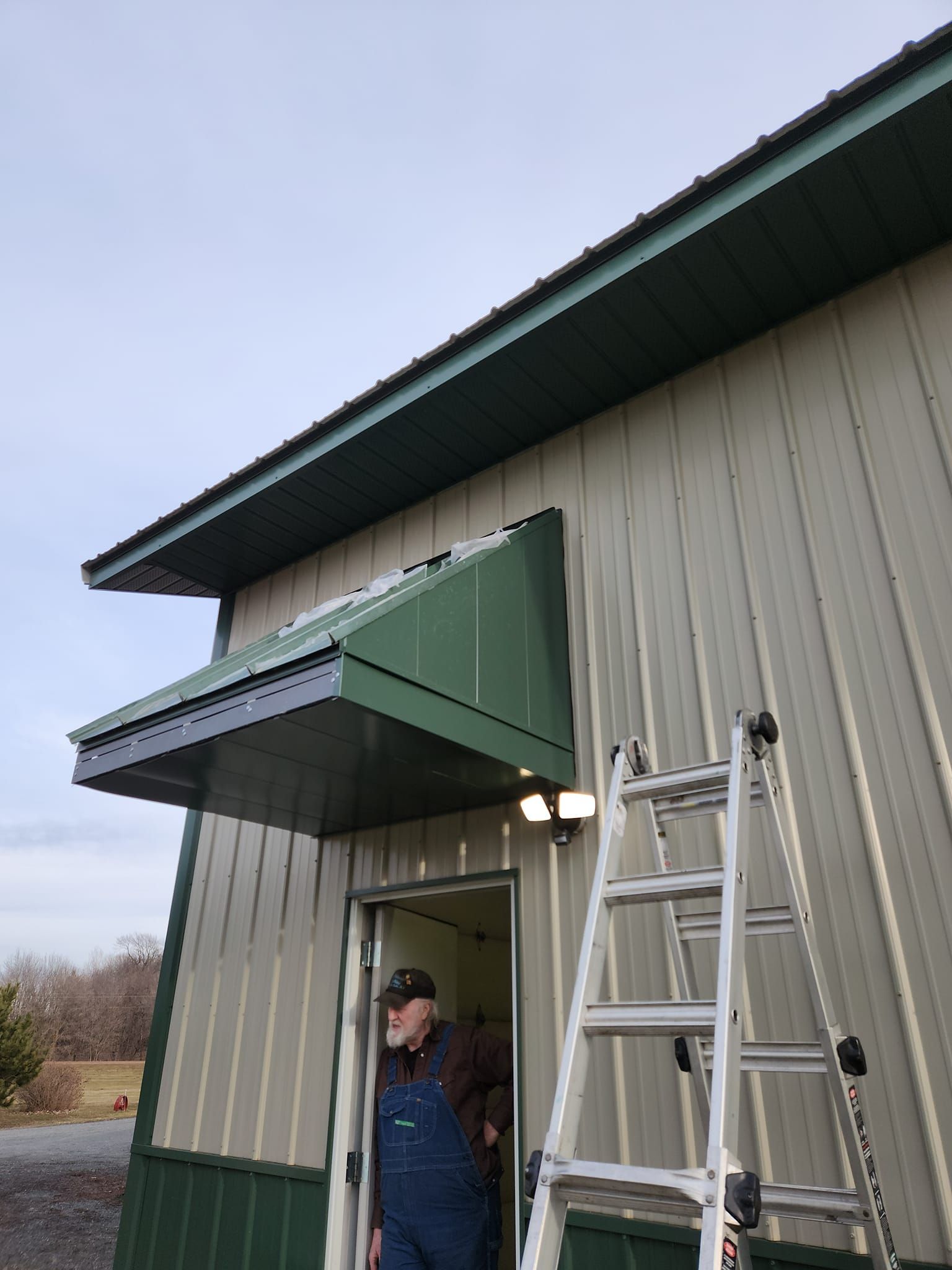 A man is standing in the doorway of a building next to a ladder.