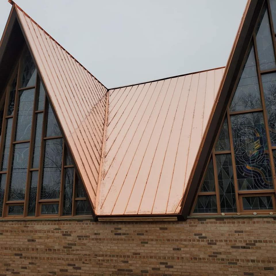 A brick building with a copper roof and stained glass windows